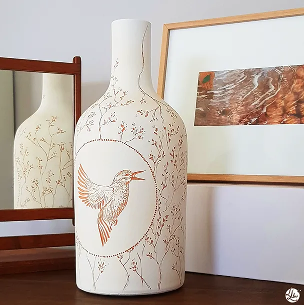 Poettery, gravure sur poterie d'un oiseau martin-pêcheur en vol entouré d'un motif végétal, par lletc